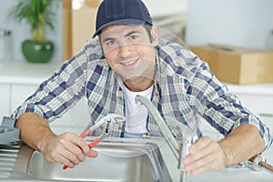 man fixing sink pipe in kitchen