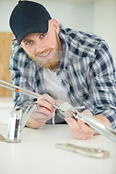 man fixing sink pipe in kitchen