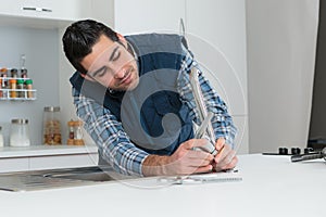 Man fixing tap with pliers at home in kitchen