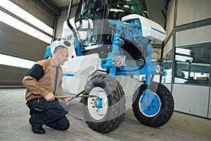 Man fixing tractor in agro-industrial hardware