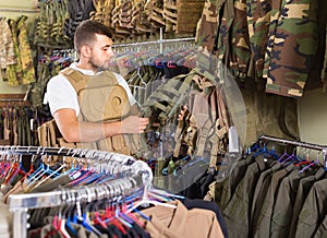 man with flak jacket in hands in airsoft market