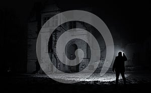 A man with a flashlight near the ruins of an old castle