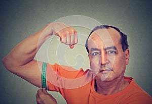 Man flexing his muscle measuring his biceps. Fitness goal achievement result