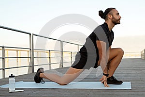 man flexing legs in kneeling hip flexor stretch exercising outdoors