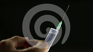 Man flicks syringe prior to drug injection, to collect and release the air out of the syringe.