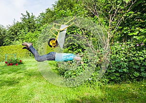 Man flies with wheelbarrow in a bush.