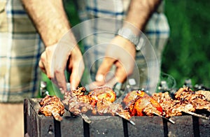 Man Flips Meat Skewers at Summer Barbecue photo