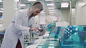 Man flips on the tablet near laboratory machine