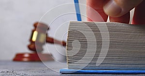 A man flips through a thick book against the backdrop of a judge\'s gavel