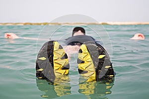 Man floating on water with shoes