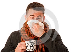 Man with flu and fever wrapped in scarf holding cup of healing t