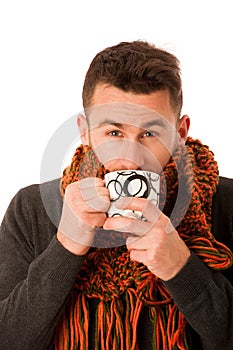 Man with flu and fever wrapped in scarf holding cup of healing t