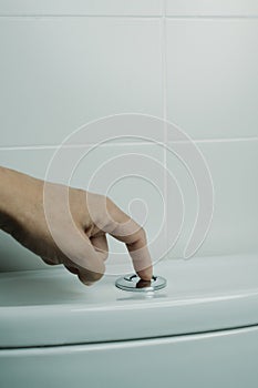 man flushes the toilet by pressing the button