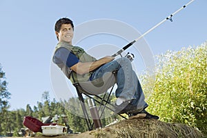 Man fly fishing, sitting on collapsible chair photo