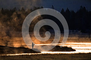 Man Flyfishing in Early Morning Light Mist from River Golden Sun