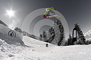 A man flying through the air while riding a snowboard down a snowy hill