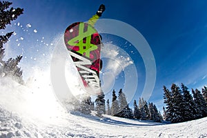 A man flying through the air while riding a snowboard down a snowy hill