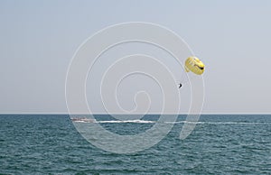 Man flying on a parachute behind above the sea