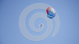 Man flying on parachute. In blue sky