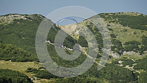 Man Flying Paraglider Over a Mountainous Landscape. Concept of Freedom, Extreme Sports, Adrenaline Rush, Adventure