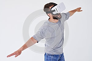 Man flying with stretched hands as he is using VR glasses