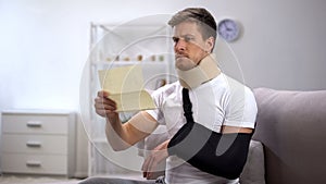 Man in foam cervical collar and arm sling reading medical bill, shocking price