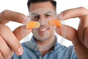 Man with foam ear plugs against white background, focus on hands