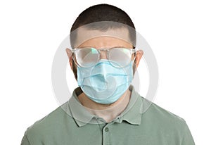 Man with foggy glasses caused by wearing disposable mask on white background. Protective measure during coronavirus pandemic