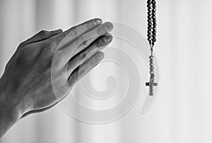 Man folded hands in prayer with rosary cross.