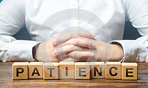 Man folded his hands on a background of blocks with the word Patience. Patience in anticipation, perseverance. Resistance