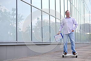 Man with folder rides GyroScooter near glass photo
