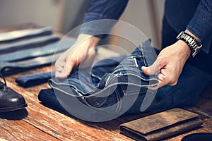 Man folding jeans on wooden table