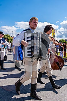 A man in folk costume plays the accordion in the procession