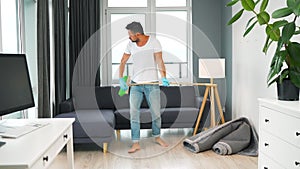 Man fooling around while cleaning the house and imagines himself a rock star, plays the broom like a guitar. Slow motion