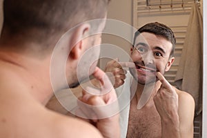 Man forcing a smile in the bathroom mirror