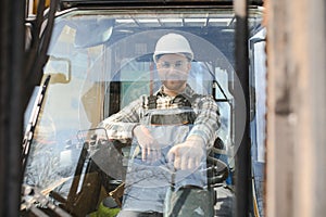 A man on a forklift works in a large warehouse, unloads bags of raw materials