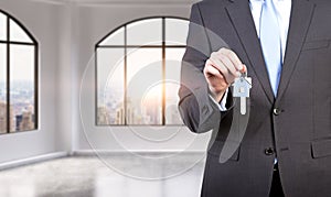 A man in formal suit holds a key in a modern loft panoramic apartment or office. Rent or buy new home or office. New York view. A