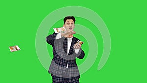 Man in formal suit throwing money in the air on a green screen, chroma key.