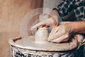 Man forms a white clay product on a pottery wheel closeup