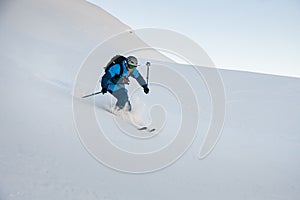 Man freerider in helmet skillfully skiing on fresh powder snow in mountains.