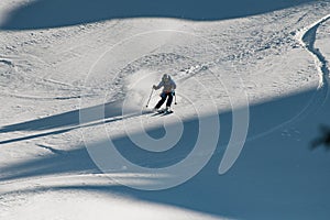 Man freerider with ski quickly slides down a mountain slope covered powdery snow.