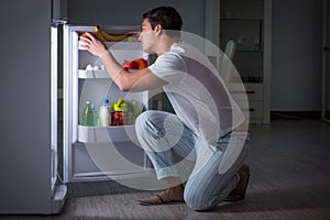 The man at the fridge eating at night