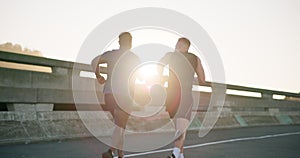 Man, friends and running in city for fitness workout, outdoor exercise or training together in urban town. Rear view of