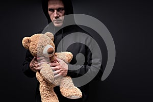 Man with frightening look holding teddy in hands, toy is simulating child abuse