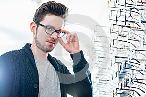 Man in front of shelf with glasses in optician shop