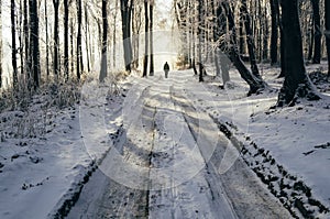 Man on frozen winter road in the forest
