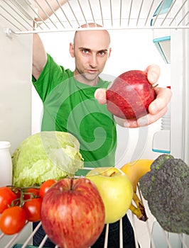 Man and fruits in refrigerator