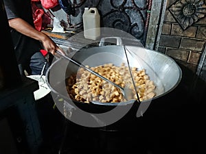 man frying cripsy tofu at big pan, using used cooking oil or minyak jelantah