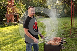 Man is frying meet in garden. Food on skewer, grill, barbecue