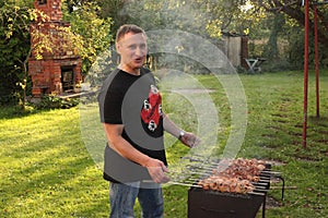 Man is frying meet in garden. Food on skewer, grill, barbecue